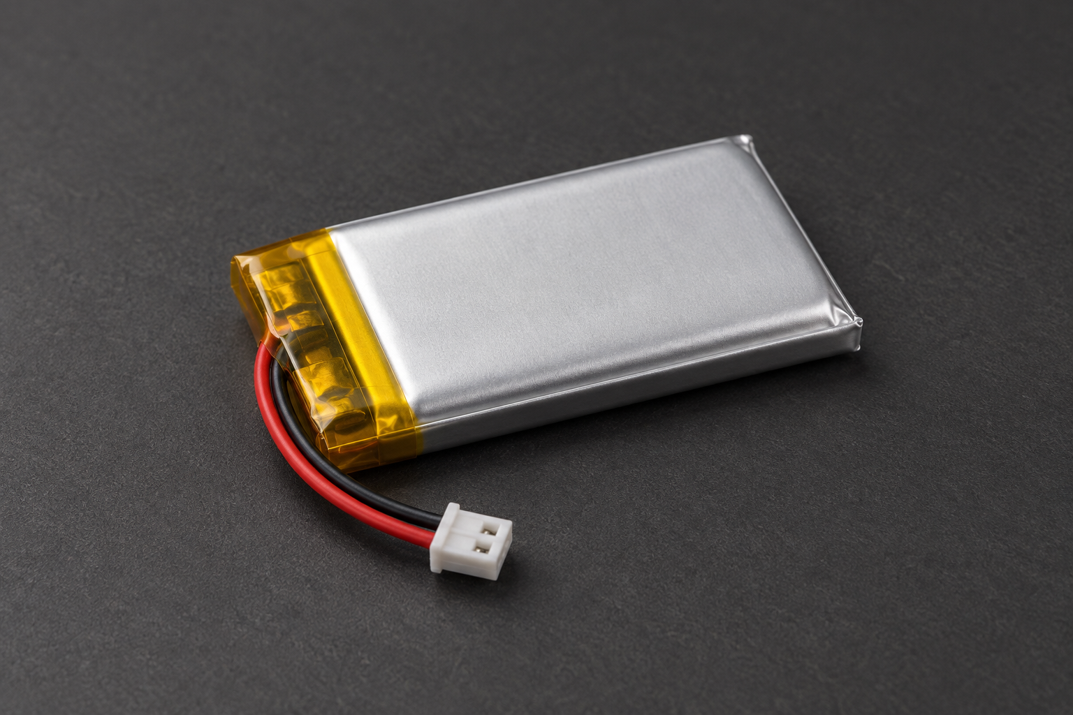 Small silver pouch battery with red and black leads and a two-pin connector